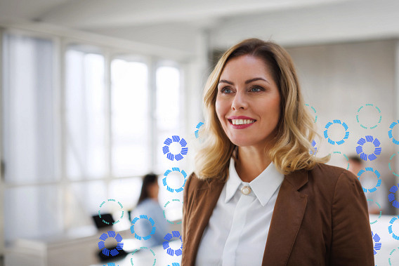 A woman in a brown blazer and a white shirt smiling in an office setting